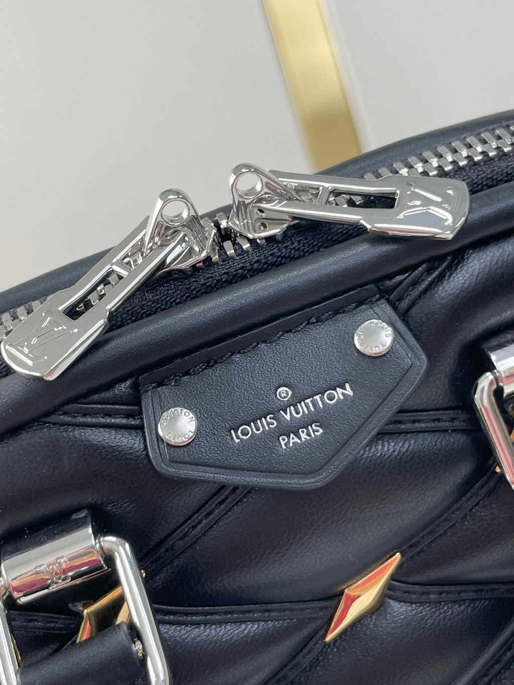 NANO ALMA 18 IN SCHWARZEM GESTEPPTES LAMMLEDER MIT GOLDENEN UND SILBERNEN BESCHLÄGEN