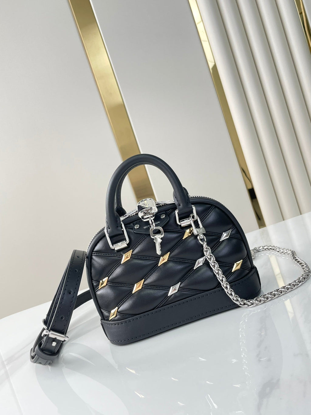 NANO ALMA 18 IN SCHWARZEM GESTEPPTES LAMMLEDER MIT GOLDENEN UND SILBERNEN BESCHLÄGEN