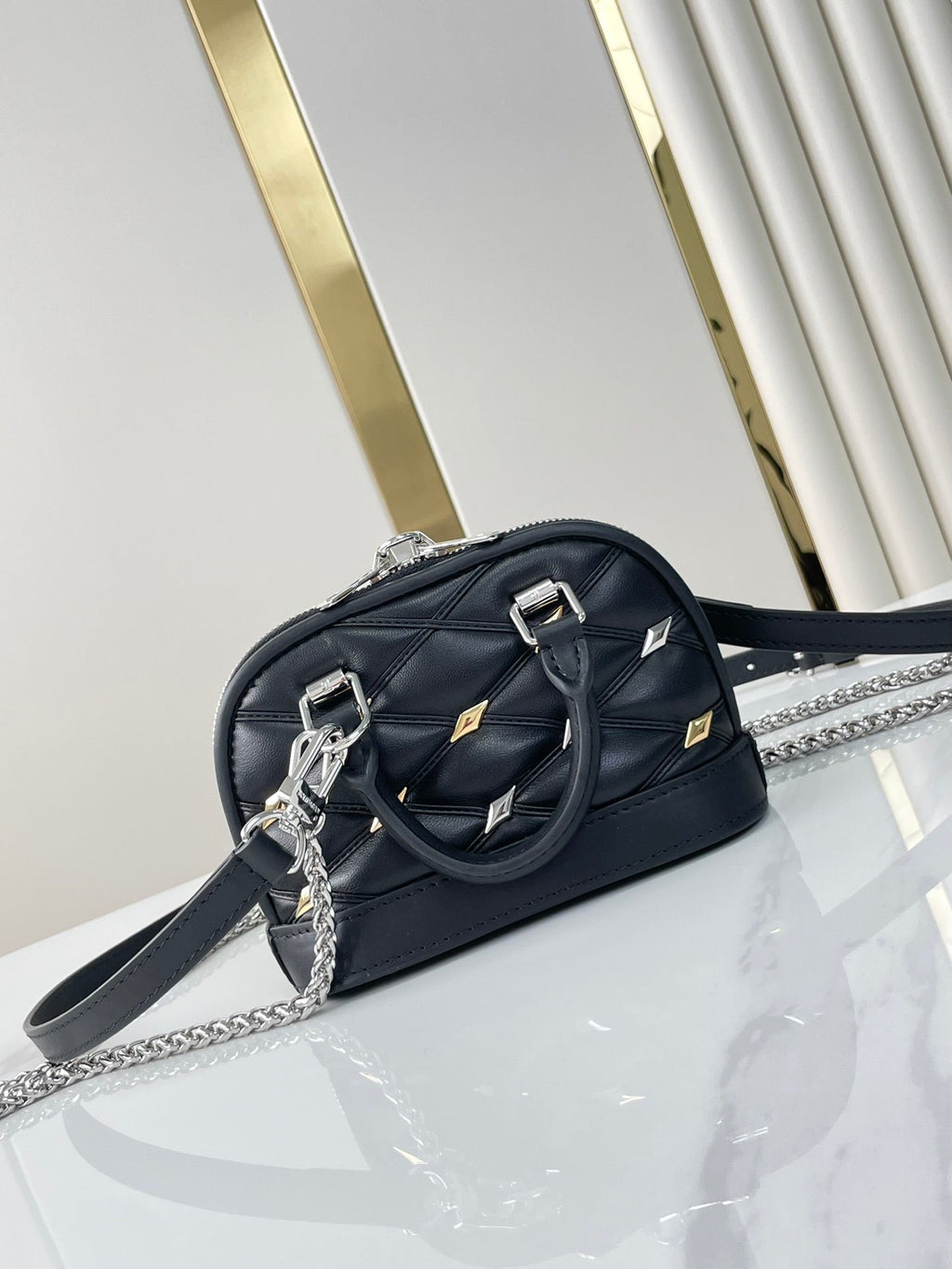 NANO ALMA 18 IN SCHWARZEM GESTEPPTES LAMMLEDER MIT GOLDENEN UND SILBERNEN BESCHLÄGEN