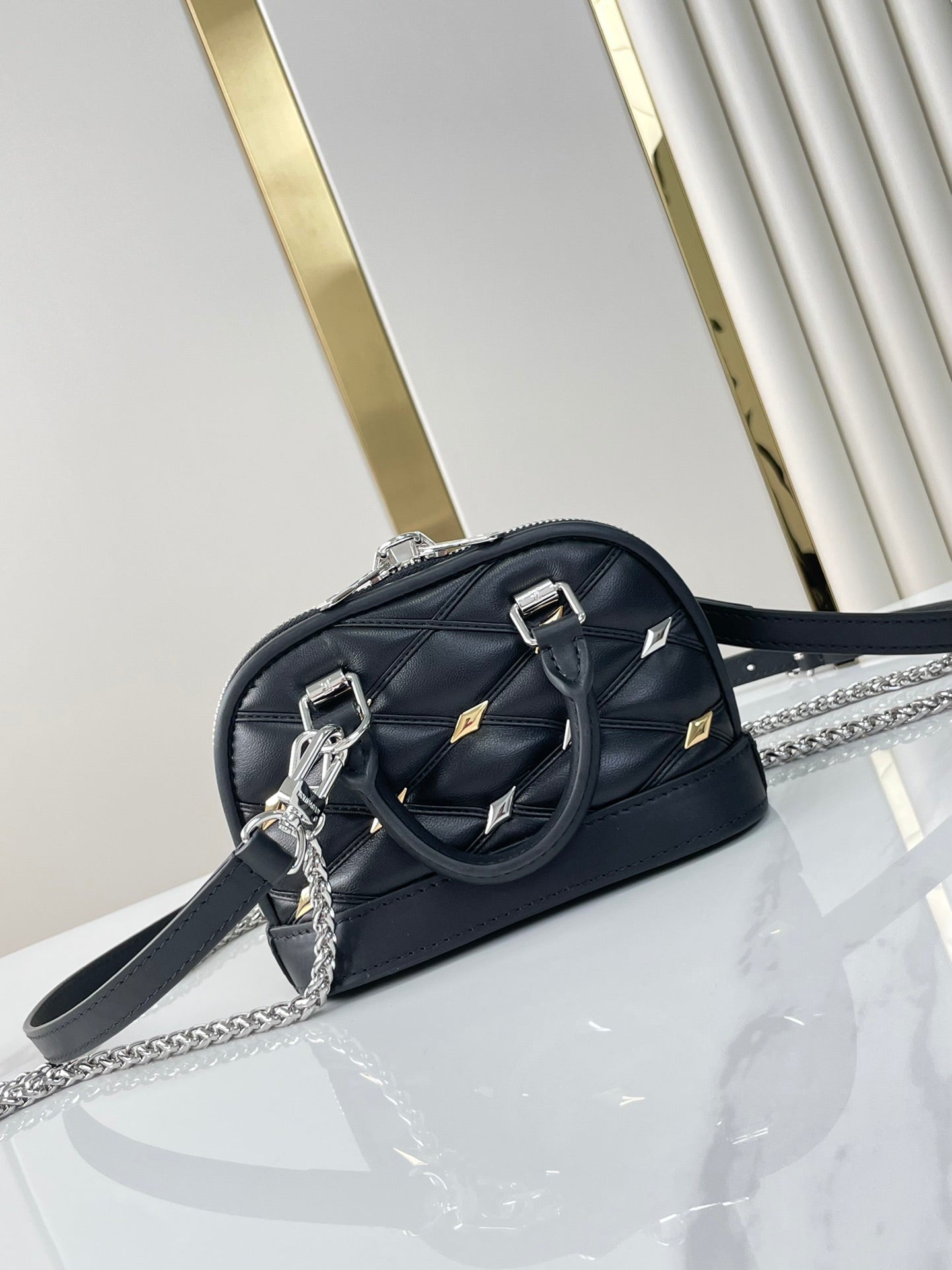 NANO ALMA 18 IN SCHWARZEM GESTEPPTES LAMMLEDER MIT GOLDENEN UND SILBERNEN BESCHLÄGEN